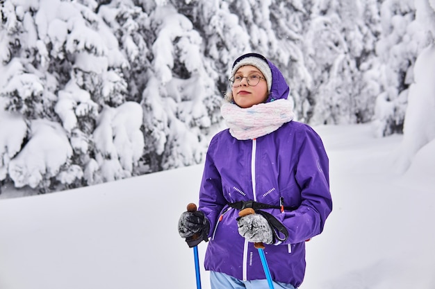 Chica esquiador aficionado camina en bosque nevado de invierno