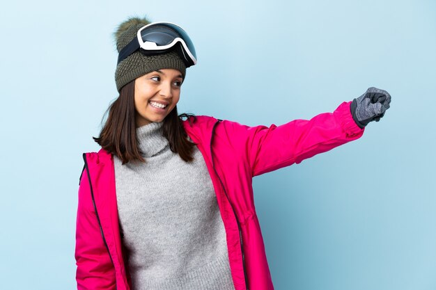 Chica esquiador con gafas de snowboard sobre aislados dando un gesto de pulgar hacia arriba