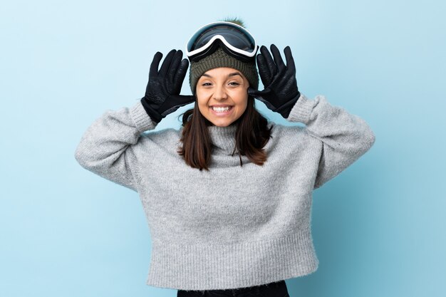 Foto chica de esquiador de raza mixta con gafas de snowboard sobre fondo azul aislado contando diez con los dedos