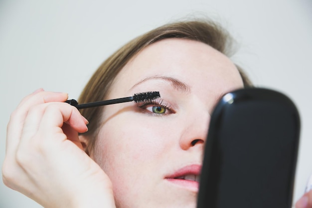 Chica está aplicando maquillaje Máscara negra en las pestañas Concepto de foto de belleza