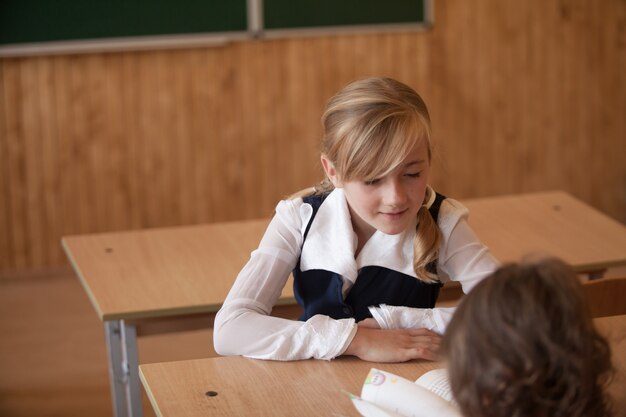 Chica está estudiando en el aula en el escritorio.