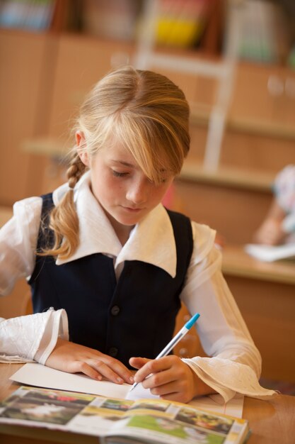 Chica está estudiando en el aula en el escritorio.