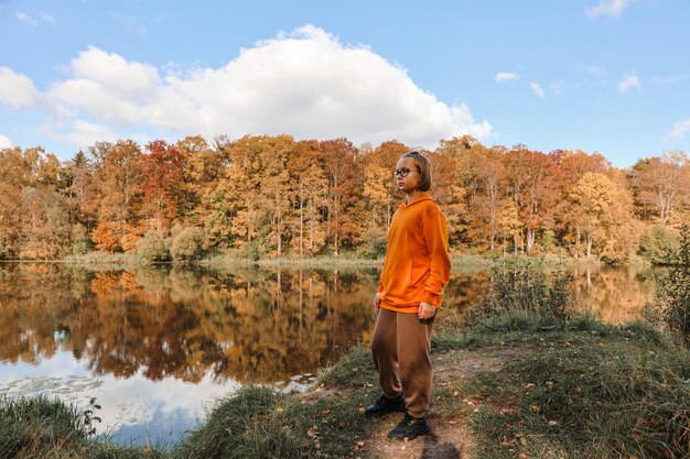 Chica está en el parque de otoño Atmósfera otoñal vista panorámica del río