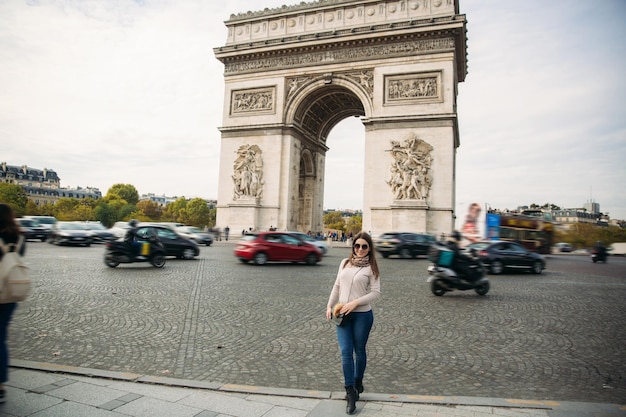 La chica está de pie ordenada en el arco triunfal.