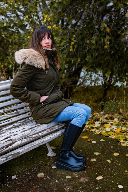 La chica está sentada en un banco en un día de otoño