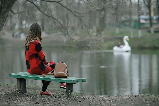 chica está sentada en un banco de jardín / hermosa modelo posando sentada en un banco en el parque de la ciudad, hermosa chica