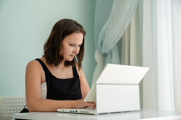La chica está sentada frente al transformador de la computadora portátil en el escritorio. concepto de trabajo remoto y educación