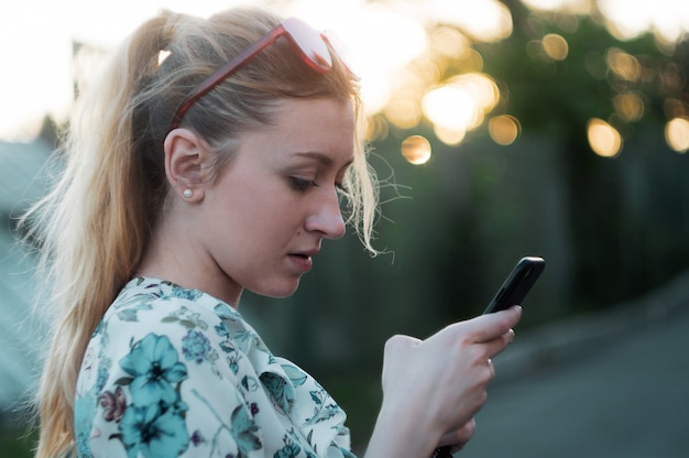 Chica está usando el teléfono al atardecer en el parque