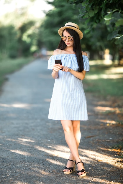 Chica está usando el teléfono caminando en el parque