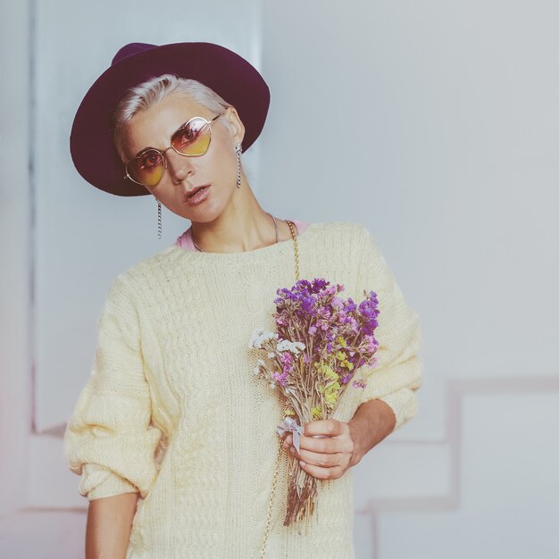 Chica con estilo campestre. Sombrero de fieltro y ramo de otoño.