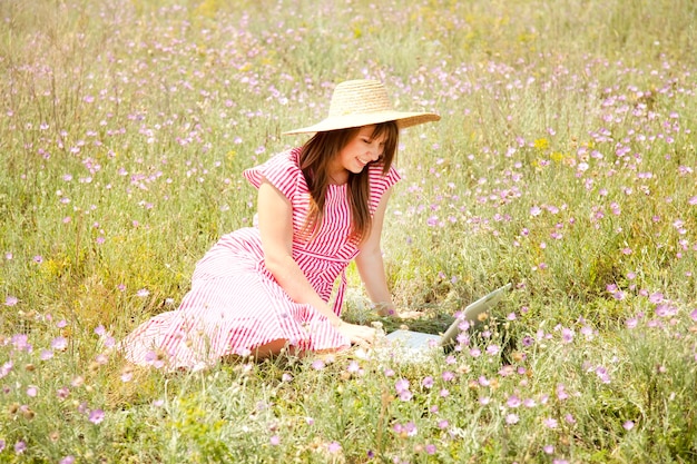 Chica de estilo retro en el campo con portátil.