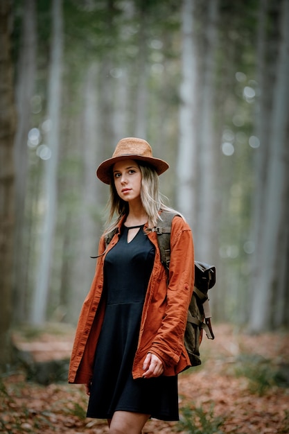 Chica de estilo con sombrero con mochila en un horario de verano Bosque de coníferas mixto