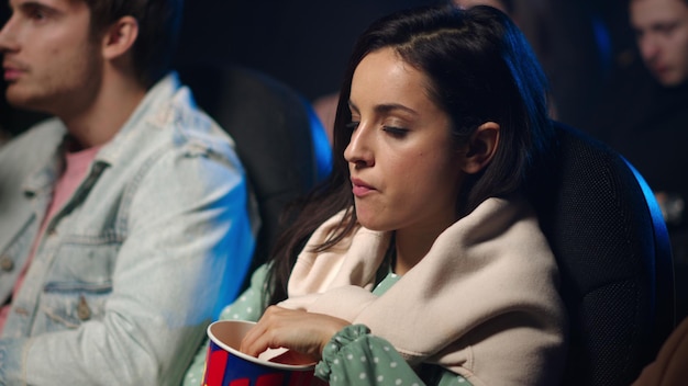 Chica estresada viendo una película en el pasillo oscuro Mujer bonita sorprendente en el cine