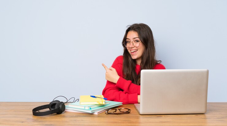 Foto chica estudiante adolescente estudiando en una mesa apuntando hacia atrás