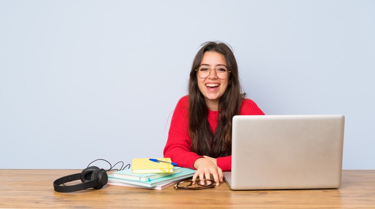 Foto chica estudiante adolescente estudiando en una mesa sonriendo