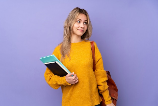 Chica estudiante adolescente en púrpura haciendo dudas gesto mirando hacia el lado