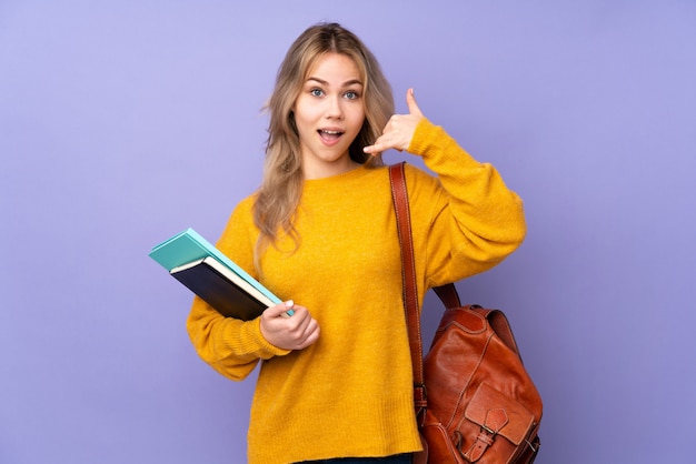 Chica estudiante adolescente ruso en pared púrpura haciendo gesto de teléfono. Llámame signo