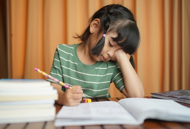 Foto chica estudiante asiática aburrida haciendo su tarea