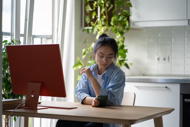 Chica estudiante asiática que usa el teléfono móvil como herramienta de estudio en el aprendizaje en línea