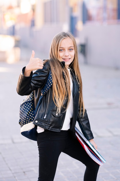 Chica estudiante de camino a la escuela haciendo gestos positivos