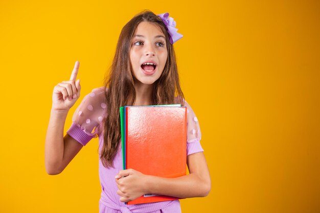 Chica estudiante caucásica con libros en sus manos y su dedo hacia arriba. De vuelta a la escuela