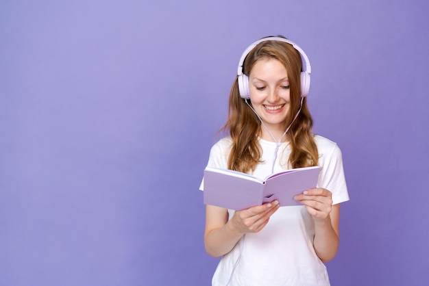 Chica estudiante encantadora escuchando música a través de auriculares tiene un abierto