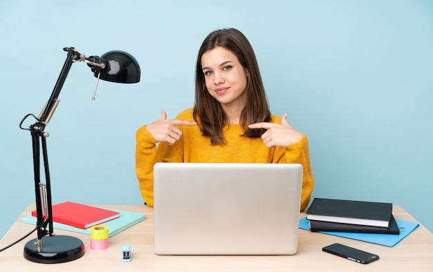 Chica estudiante estudiando en su casa en azul orgulloso y satisfecho de sí mismo