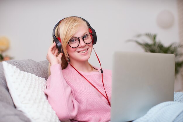 Chica estudiante feliz de comunicarse con amigos auriculares a través de Internet