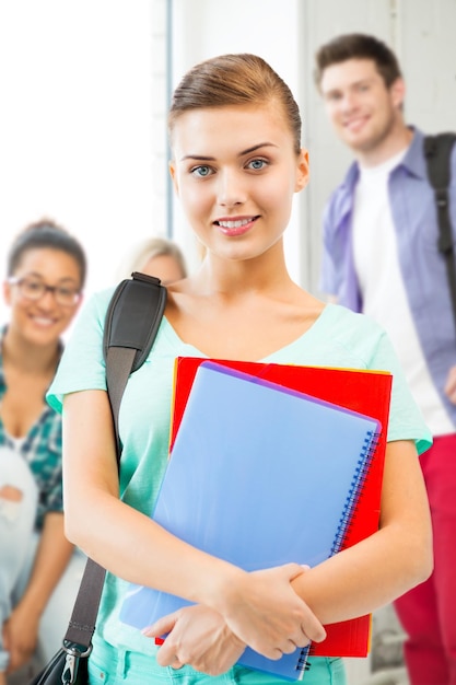 Chica estudiante feliz con mochila escolar y cuadernos en la escuela