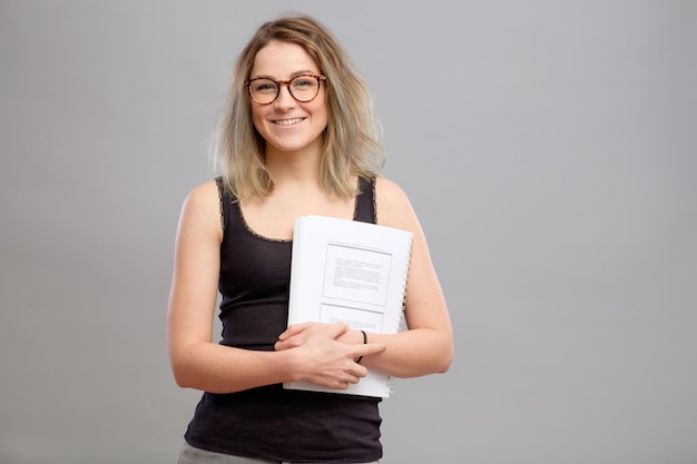 Chica estudiante con gafas sosteniendo un libro