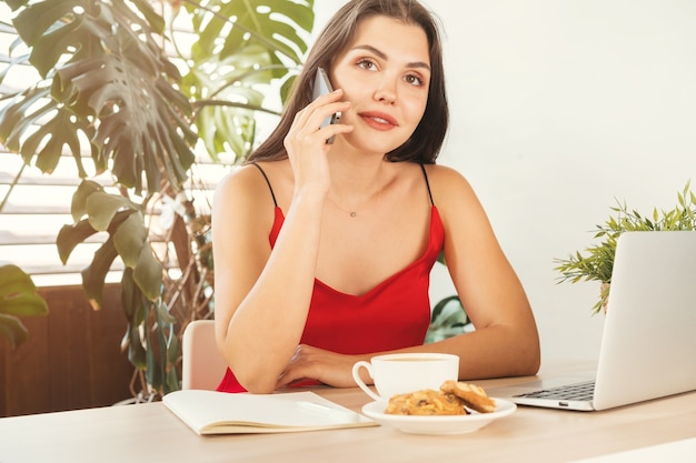 Chica estudiante hablando por teléfono mientras está sentado en la cafetería