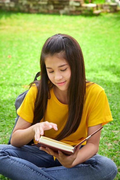 Chica estudiante leyendo un libro en el parque