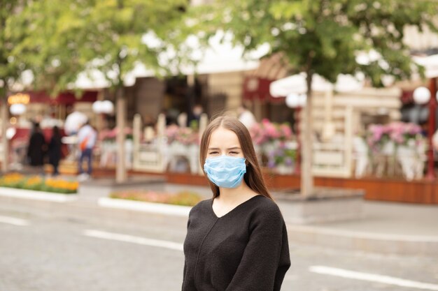 Chica estudiante con una máscara protectora camina por la ciudad