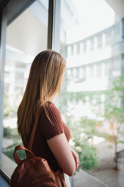 Chica estudiante mirando por la ventana durante un receso de clase