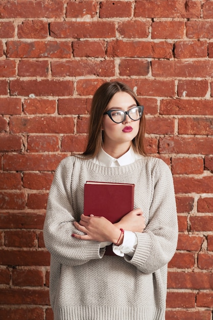 Chica estudiante de pie con libro de texto