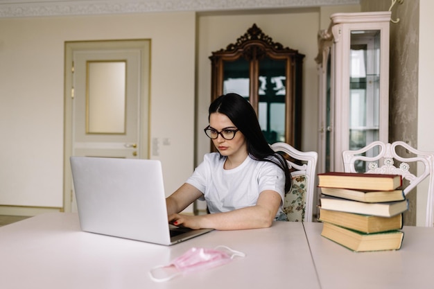 Chica estudiante sentada en casa mirando la pantalla del portátil escuchando ejercicio estudiando idiomas extranjeros en línea haciendo notas vista lateral Operador del centro de llamadas trabajando en interiores Concepto de aprendizaje electrónico de tecnología