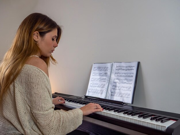 Foto chica estudiante tocando el piano con partituras