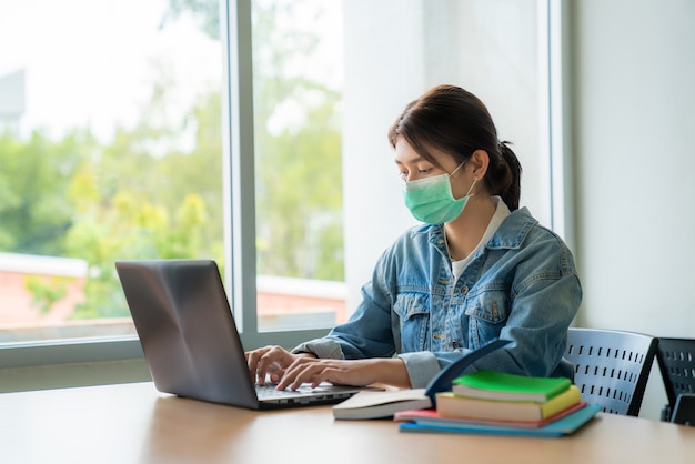 Chica estudiante universitaria asiática con máscara médica protectora facial para protección