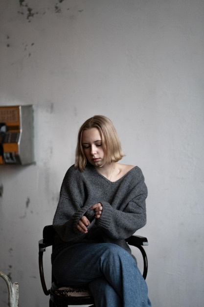 Una chica europea con cabello rubio corto posa en un suéter de punto para un catálogo de ropa