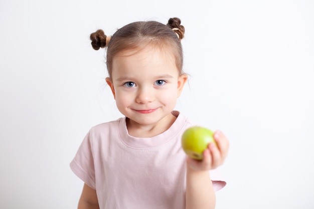 Chica europea con ojos azules tiene una manzana verde en su mano