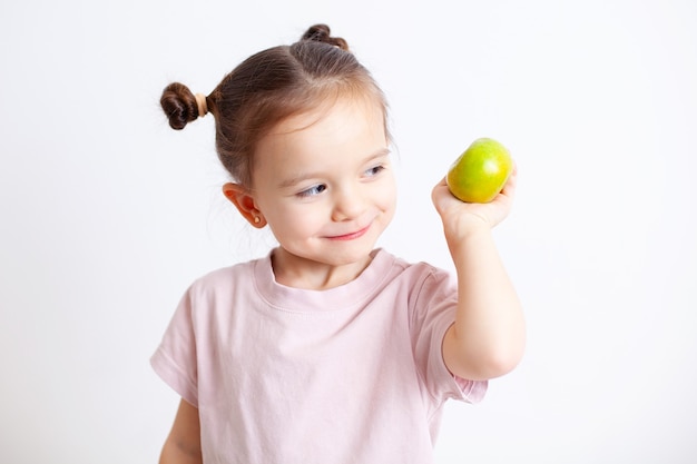 Chica europea con ojos azules tiene una manzana verde en su mano