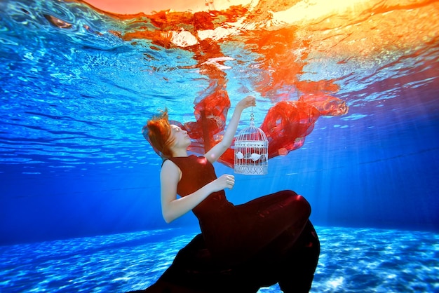 Una chica fabulosa con un hermoso vestido en una piscina nada y sueña en el fondo de luces brillantes