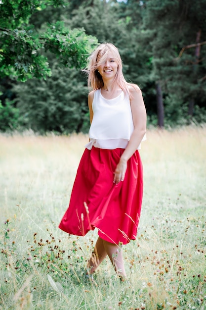 La chica de la falda roja está bailando en la naturaleza.