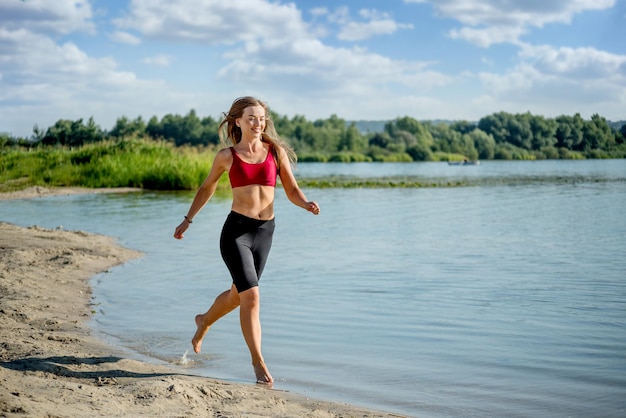 Chica feliz corre sobre el agua en la orilla del lago