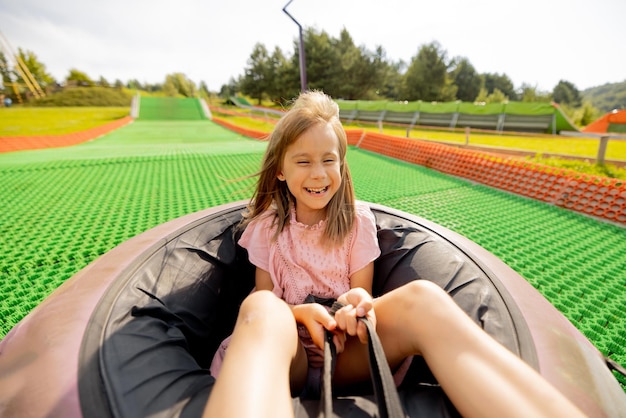 Una chica feliz desciende en un tubo de trineo inflable en un parque de atracciones
