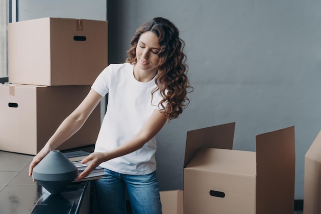 Chica feliz desempacando cajas de cartón Reubicación en un nuevo apartamento Hipoteca y concepto de bienes raíces