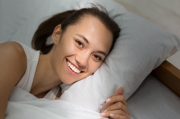 Chica feliz despierta y sonriendo a la cámara