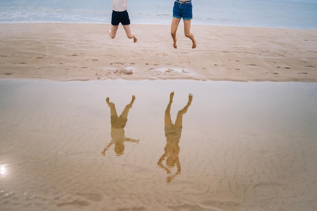 Chica feliz divirtiéndose en la playa tropical y corriendo y chapoteando en aguas poco profundas saltando al aire