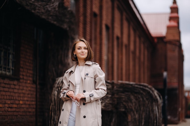 Una chica feliz y elegante con un abrigo gris camina por la ciudad