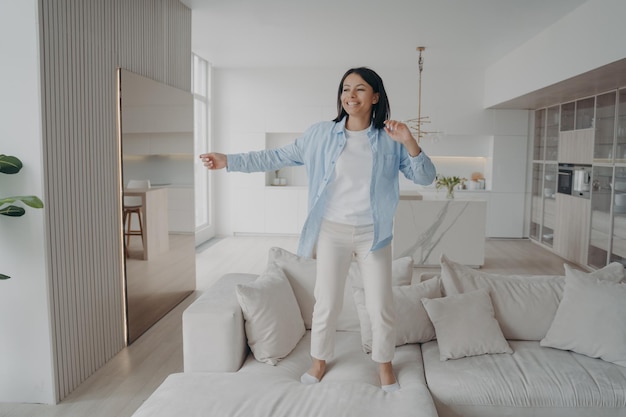 Chica feliz emocionada está escuchando música cantando y bailando en el sofá Sueños y libertad